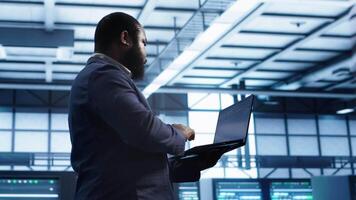 Technician in data center workspace running system diagnostic tests and error checking utilities to fix issues. Employee looks for network issues affecting rigs performance and connectivity, camera A video