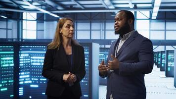 Teamworking technicians in high tech data center workspace looking at hologram visualization. Programmer and colleague working on securing server room hardware using AR tech, camera A video