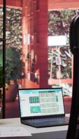 Vertical Empty home office with a laptop showing financial data sales reports, setup of a small business owner working remotely. Finance and economy infographics balance. Money management. video