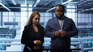 System administrators looking at holograms in data center, doing swiping motions hand gestures. Server farm workplace employees interacting with augmented reality tech, camera A video