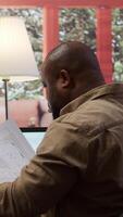 Vertical Businessman analyzing architecture blueprints for new office space layout, looking to relocate startup. Entrepreneur conducts an office hunt, business development and strategy planning. Camera B. video