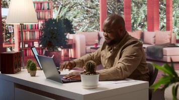 Freelancer using his laptop to manage business analytics and financial planning, ensuring successful telecommuting. Working on budget and project development from his home office. Camera A. video