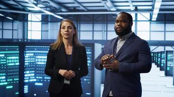 Team of admins in high tech data center looking at hologram visualization. Engineer and coworker working on securing serves using AR tech, preventing hacker attacks, camera A video