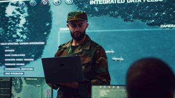 Army general managing air traffic control for military aircraft within the operational area, uses radar surveillance. Follows vessels on navy reconnaissance satellite system, big screen. Camera A. video
