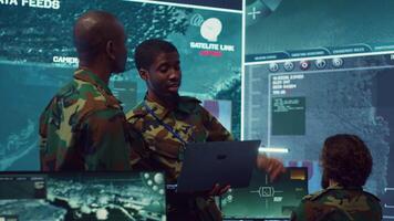 Army commanders overseeing field operations with real time data registered on surveillance CCTV systems. Military officials examining mission details, army defense program in power base. Camera A. video