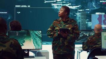 Female military officer supervising radar surveillance footage to input and process tactical data on a big screen. Woman uses global reconnaissance in creating battlefield maps. Camera A. video