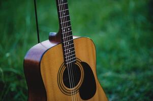 Acoustic guitar, stringed musical instrument, placed in the grass, classical guitar, playing music and relaxing. photo