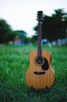 Acoustic guitar, stringed musical instrument, placed in the grass, classical guitar, playing music and relaxing. photo