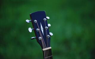 Acoustic guitar, stringed musical instrument, placed in the grass, classical guitar, playing music and relaxing. photo