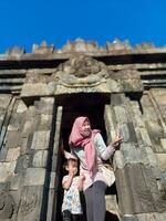 Mother and child enjoy a holiday with a view of Plaosan temple, good for blog, ads, template, banner etc photo