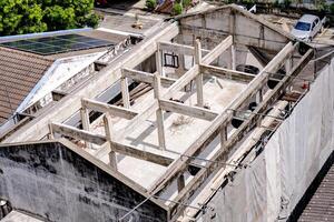 Abandoned concrete building under construction with old architectural features, set against a clear sky in an urban environment. The roof of the house has solar panels installed to use clean energy. photo