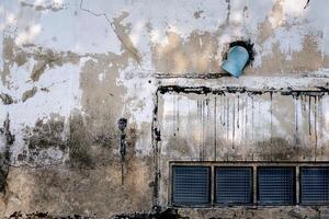 Fragment of an old cracked wall with transparent block for light to penetrate. Grunge wall of the old house. Large blue pipe end. Textured background. photo