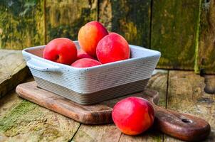 apricots in a white ceramic bowl on a wooden background on a kitchen board photo
