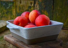 apricots in a white ceramic bowl on a wooden background on a kitchen board photo