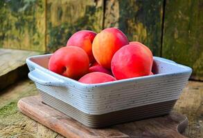 apricots in a white ceramic bowl on a wooden background on a kitchen board photo
