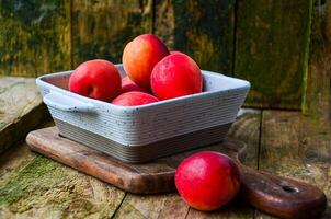 apricots in a white ceramic bowl on a wooden background on a kitchen board photo