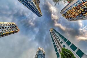 view from below into storm sky with dark clouds of large modern skyscraper residential complex photo