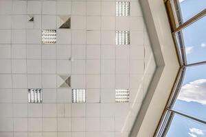 cassette stretched or suspended ceiling with square halogen spots lamps and drywall construction in empty room in house or office. Looking up view photo