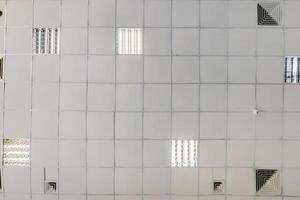 cassette stretched or suspended ceiling with square halogen spots lamps and drywall construction in empty room in house or office. Looking up view photo