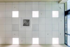 cassette stretched or suspended ceiling with square halogen spots lamps and drywall construction in empty room in house or office. Looking up view photo