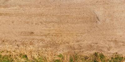 view from above on texture of dry muddy road with tractor tire tracks in countryside photo