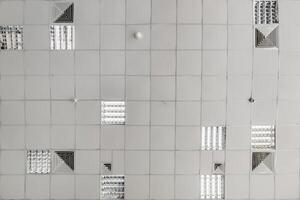 cassette stretched or suspended ceiling with square halogen spots lamps and drywall construction in empty room in house or office. Looking up view photo