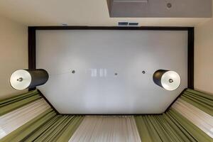 suspended ceiling with halogen spots lamps and drywall construction in empty room in apartment or house. Stretch ceiling white and complex shape. photo
