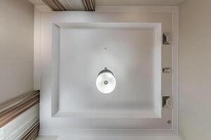 suspended ceiling with halogen spots lamps and drywall construction in empty room in apartment or house. Stretch ceiling white and complex shape. photo