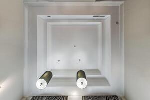 suspended ceiling with halogen spots lamps and drywall construction in empty room in apartment or house. Stretch ceiling white and complex shape. photo