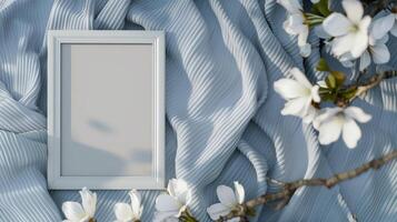 A white frame mockup, against a blue blanket with white flowers. photo