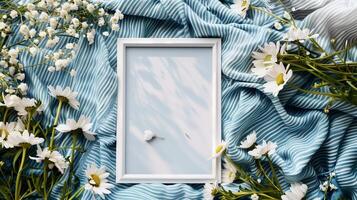 A white frame mockup, against a blue blanket with white flowers. photo