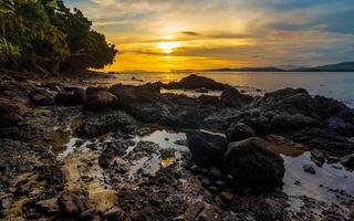 Beautiful calm sunset at beach with rocks photo