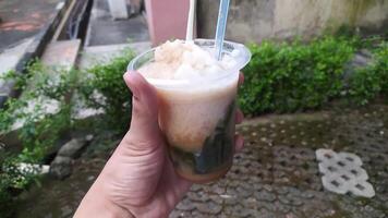 a typical Indonesian drink called es cincau, made from grass jelly with coconut milk sauce, topped with liquid sugar, and added with ice to make it colder. photo