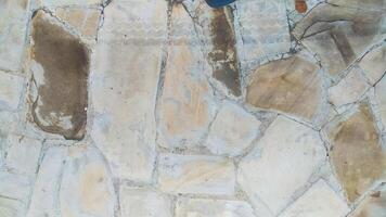 The texture of a road is made from rough-textured stone tiles with different shape variants and is dominated by cream and white colors, very suitable for background and texture design. photo