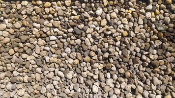 Pebbles piled up and scattered on the ground on a road create an interesting texture, suitable for photo backgrounds and texture designs