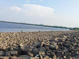 the sunny coastline is littered with large, sharp rocks that divide the sea from the land. photo