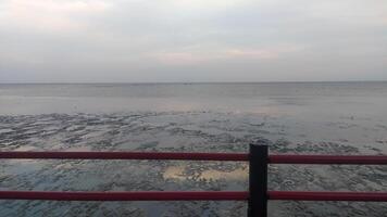 a view of the beach facing directly to the sea in a beautiful afternoon, the beach is visible at low tide making the sand very visible from the top of the fence photo