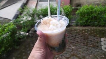 a typical Indonesian drink called es cincau, made from grass jelly with coconut milk sauce, topped with liquid sugar, and added with ice to make it colder. photo