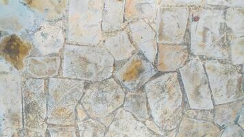 The texture of a road is made from rough-textured stone tiles with different shape variants and is dominated by cream and white colors, very suitable for background and texture design. photo