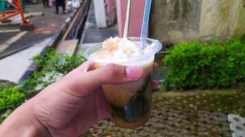 drink called es cincau, made from grass jelly with coconut milk sauce, topped with liquid sugar, and added with ice to make it colder. photo