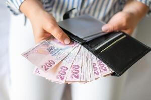 Leather wallet with money in the hands of a woman. Close-up of a woman taking a Turkish lira with a fan from her wallet, a lot of money but little value,high inflation rate in Turkey photo