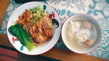 Top view of a traditional Asian noodle dish with grilled chicken, vegetables, and a side of dumpling soup video