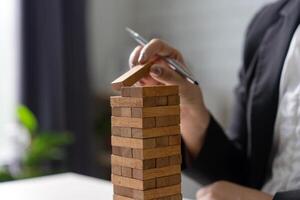 Close up of an employee's hand holding a wooden block for business planning while working on a laptop. photo