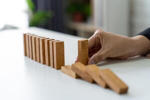 The manager's hands are stopping the falling dominoes to prevent their total collapse and ensure stability. photo