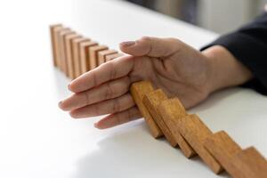 Hand stopping falling dominoes. Finance or failure concept. photo