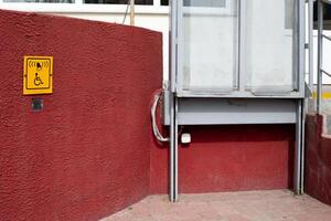Elevator for disabled people to enter the building next to sign and help button for wheelchair access photo