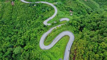 Aerial view of a road in the middle of a forest, construction of a curved road up the mountains in northern Thailand. video
