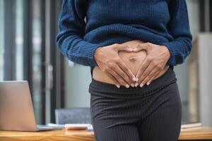 pregnant mother uses her hands to touch her stomach to comfort baby inside womb with tenderness and love for the baby. An expectant mother uses her hands to caress her belly gently and lovingly. photo