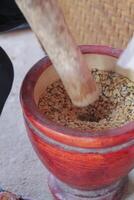 Farmers use wooden mortars and pestles to break the husks apart from the coffee beans to remove unwanted husks from coffee beans before processing them to produce high quality coffee beans for export. photo