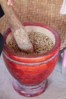 Farmers use wooden mortars and pestles to break the husks apart from the coffee beans to remove unwanted husks from coffee beans before processing them to produce high quality coffee beans for export. photo